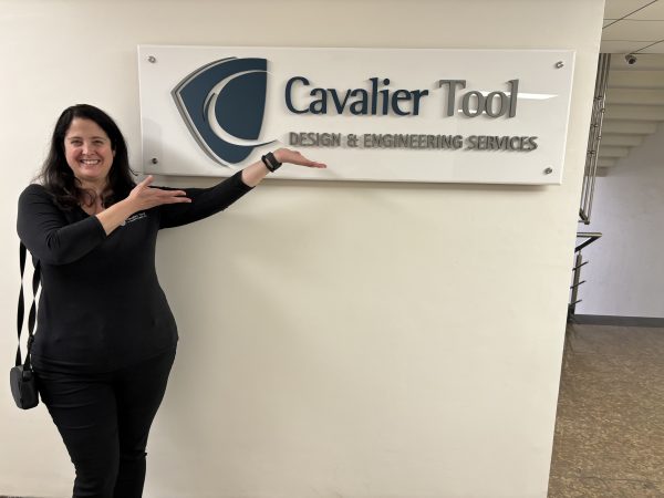 CFO Diane Woodiwiss posing with a Cavalier Tool India sign in one of Cavalier's three design offices in India.